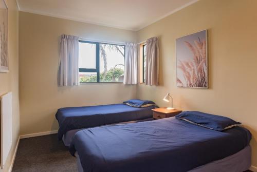 two beds in a room with a window at Bay of Islands Lodge in Paihia
