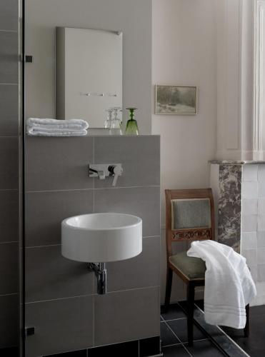 a bathroom with a sink and a chair and a mirror at Boutique Hotel Grote Gracht in Maastricht