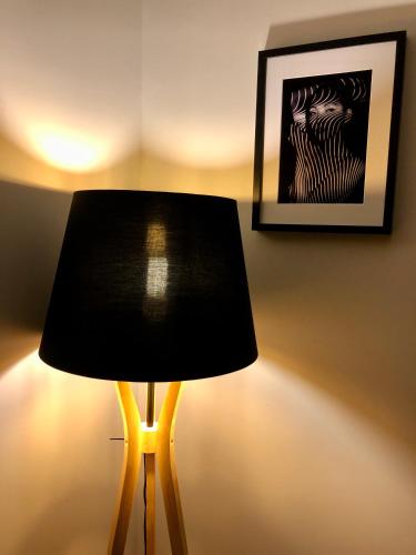 a black lamp sitting next to a wall with a picture at Appartement Cosy 600m Gare - étage 3 - balcon et calme - TV - wifi in Bernay