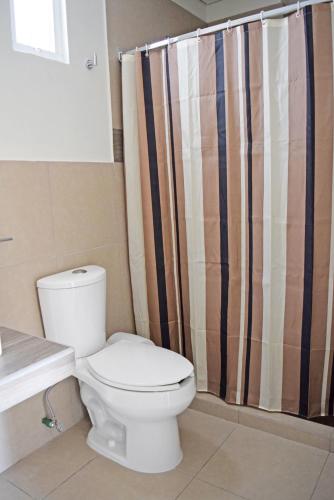 a bathroom with a toilet and a shower curtain at Hotel Guivá San Pablo in Hacienda Blanca