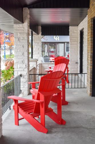 a group of red chairs sitting on a porch at Colonial Hotel & Suites in Grand Bend