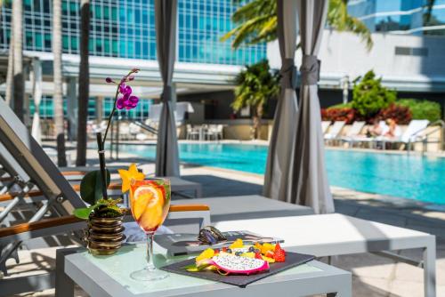 a table with a drink on it next to a pool at Hotel AKA Brickell in Miami