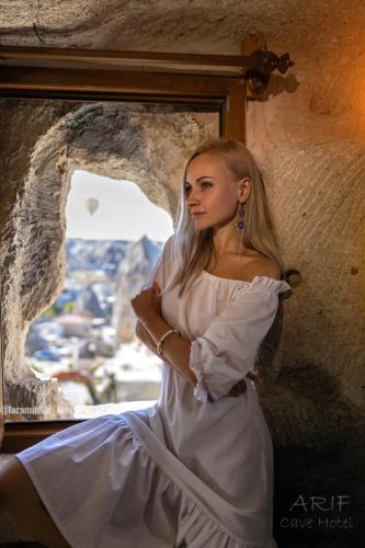 a woman in a white dress sitting in front of a window at Arif Cave Hotel in Goreme
