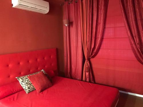 1 cama roja con cabecero rojo y ventana en La Mazmorra de Lucifer, en Madrid