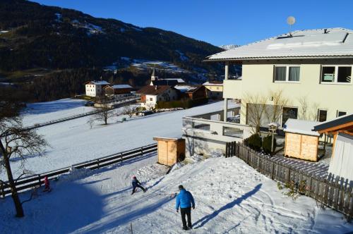 two people skiing down a snow covered slope near a house at Haus Raich in Arzl im Pitztal