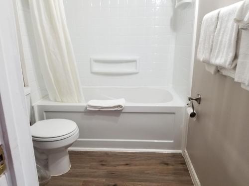 La salle de bains blanche est pourvue de toilettes et d'une baignoire. dans l'établissement Richard lake motel, à Coniston