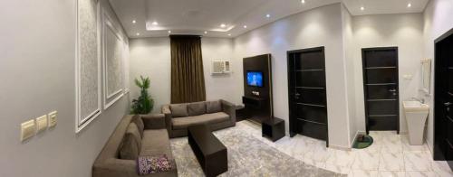 a living room with a couch and a television at Opera Suites in Muhayil