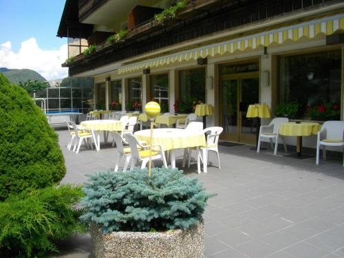 a patio with yellow tables and chairs and a building at Hotel Rodes in Ortisei