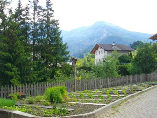 a garden with a fence and trees and a house at Hotel Rodes in Ortisei