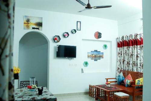 Bethel Service Villa, Mananthavady, Wayanad في واياناد: غرفة معيشة مع أريكة وتلفزيون على الحائط