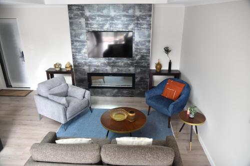 a living room with a couch and chairs and a tv at Stellar Apartment in Lake Tekapo
