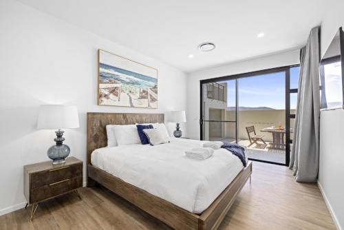 a bedroom with a large bed and a balcony at Paramount on Jarret in Coffs Harbour