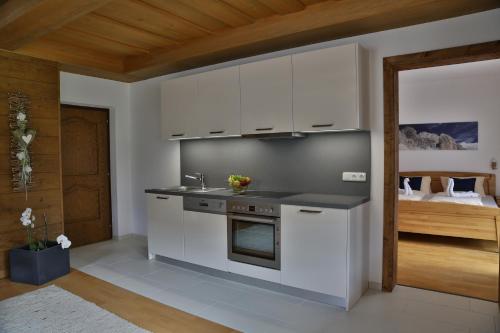 a kitchen with white cabinets and a sink and a bed at Ferienhaus Viktoria in Abfaltersbach