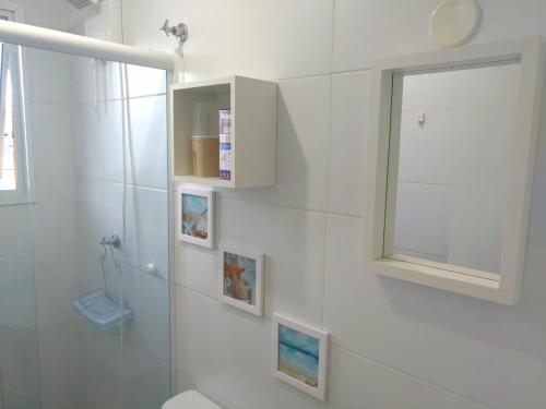 a white bathroom with a toilet and a mirror at APTo 300MTS DA PRAIA, VISTA PARA O MAR, CHURRASQUEIRA, WI-FI, AR CONDICIONADO, TOTALMENTE EQUIPADO in Ubatuba