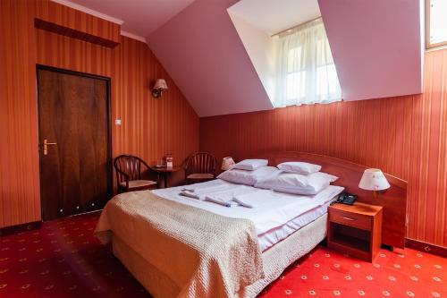 a bedroom with a bed with white sheets and pillows at Hotel Restauracja Browar Lwów w Lublinie in Lublin