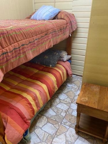 a bed with a striped blanket and a table at Hospedaje & Alojamientos Hilda in Puerto Montt