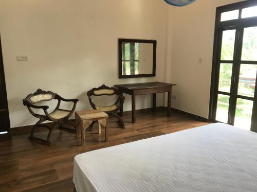 a bedroom with a bed and a table and two chairs at Villa Sea Side Beruwala in Beruwala