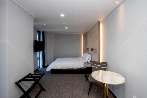 a bedroom with a bed and a table and a chair at Griffinbay Hotel in Busan
