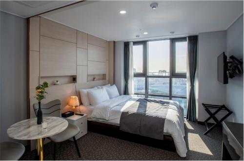 a bedroom with a bed and a large window at Griffinbay Hotel in Busan