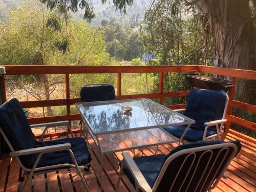 a glass table and chairs on a deck at CABAÑA ZAPALLAR BOSQUE PLAYA CON HOTTUBE in Zapallar