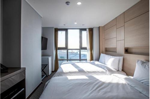 a bedroom with a large white bed and a window at Griffinbay Hotel in Busan