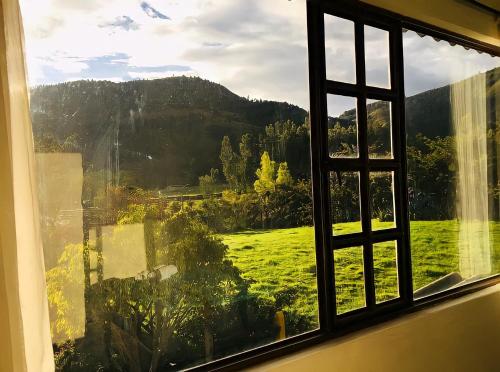 a window with a view of a green field at MALAVI Cabaña Nobsa in Nobsa