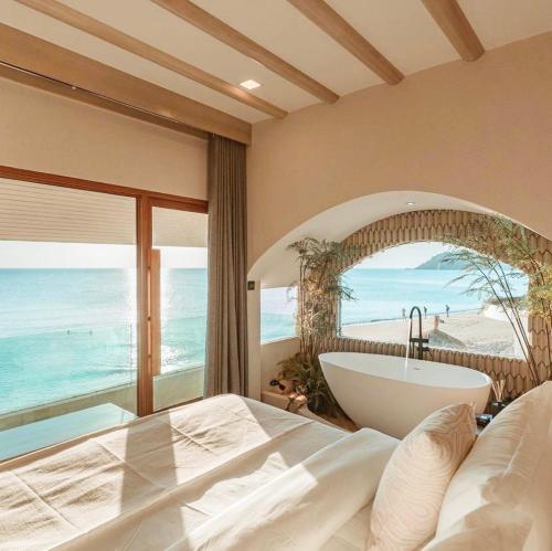 a bedroom with a tub and a view of the ocean at Maldives Beach Resort in Chao Lao Beach