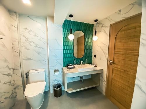 a bathroom with a sink and a toilet and a mirror at Maldives Beach Resort in Chao Lao Beach