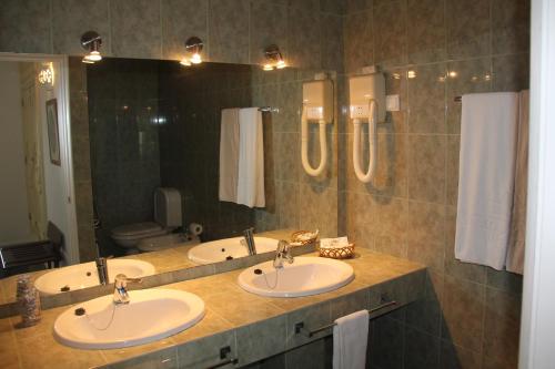 a bathroom with two sinks and a large mirror at Hotel Vasco Da Gama in Monte Gordo