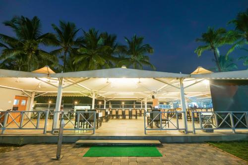 a restaurant with tables and umbrellas at night at Gold Beach Villa in Daman
