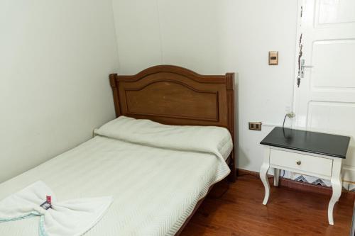a small bedroom with a bed and a table at Residencial Velia & Victoria in Cochabamba