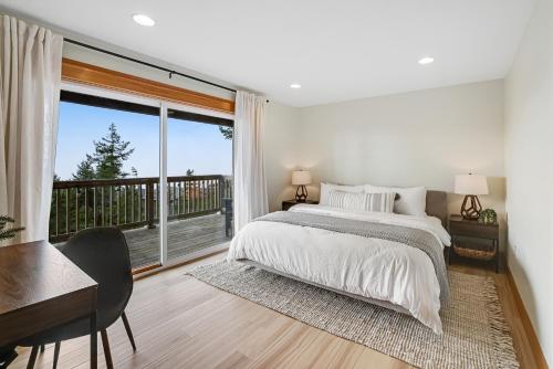 a bedroom with a bed and a desk and a large window at Three Capes Bungalow in Oceanside