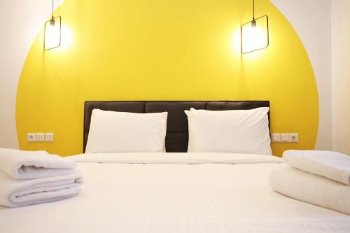 a bed with two white pillows and a yellow wall at GK Aria in Athens