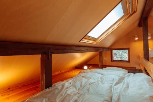 a bed in a small room with a skylight at ROKKONOMAD in Kobe