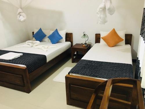 - 2 lits dans une chambre avec 2 chaises dans l'établissement Restwell Homestay, à Dambulla
