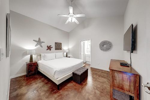 a bedroom with a white bed and a ceiling fan at Love & Luck in Corpus Christi