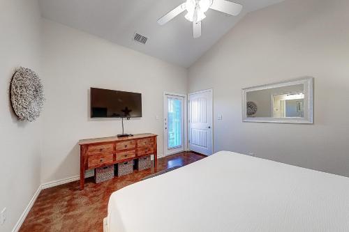 a white bedroom with a bed and a television at Love & Luck in Corpus Christi