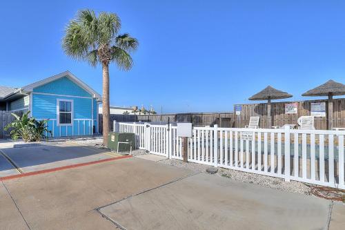 a blue house with a white fence and a palm tree at Love & Luck in Corpus Christi