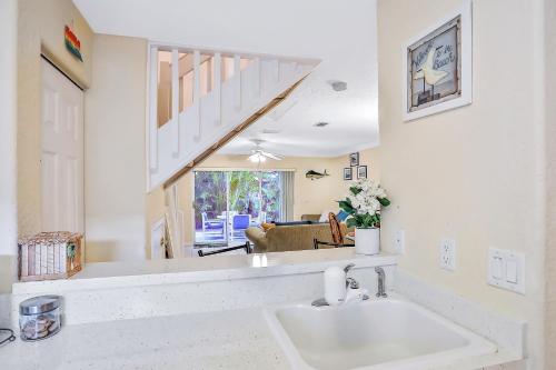 a white kitchen with a sink and a living room at Sandy Nose in Cape Canaveral