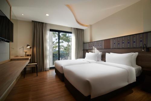 um quarto de hotel com duas camas e uma janela em Emmaline Hotel Nan em Nan