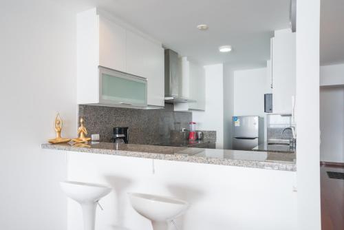 a white kitchen with white counters and white stools at Outstanding Ocean View 2BR 2BA Pool Gym by GLOBALSTAY in Lima