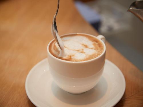 a cup of coffee on a plate with a spoon at THE GRAND HOTEL GINOWAN in Ginowan
