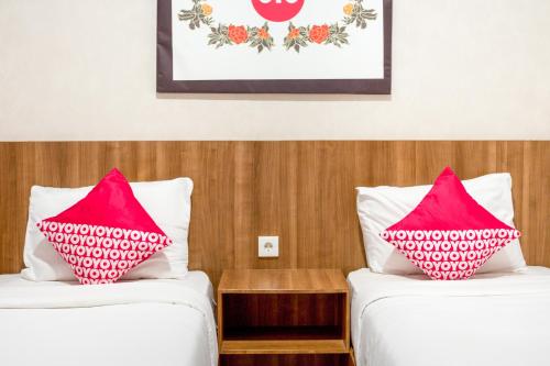 two beds in a hotel room with pink pillows at Hotel O Papakoel in Medan
