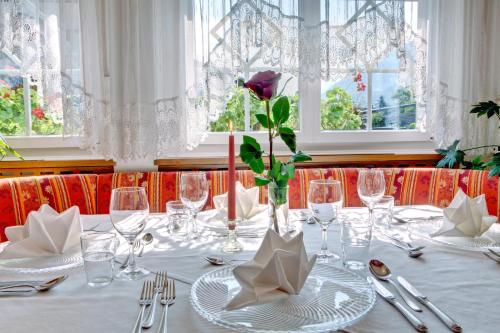 a table with glasses and a flower in a vase at Parkhotel Plauserhof in Plaus