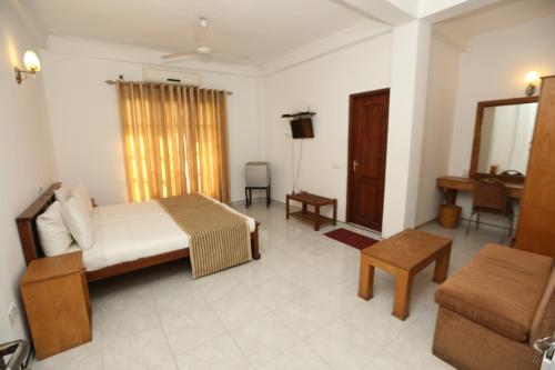a bedroom with a bed and a couch and a table at The Delight Residence in Kandy