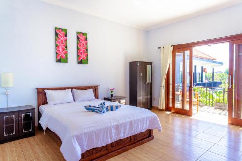 a bedroom with a large white bed and a balcony at D'Canggu Homestay in Canggu