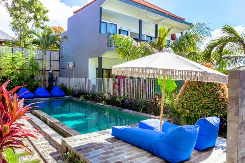 a pool with chairs and an umbrella next to a house at D'Canggu Homestay in Canggu