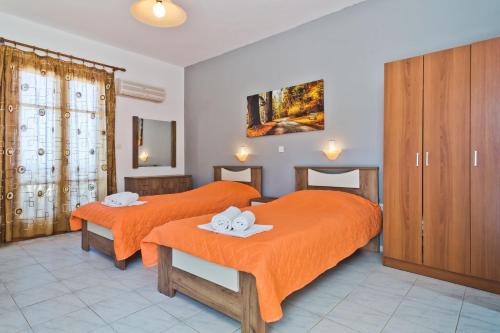 two beds in a hotel room with orange sheets at ZoeStudios-Arkasa in Arkasa