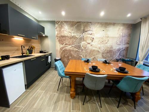 une cuisine avec une table en bois et des chaises bleues dans l'établissement Capsule Egypte - Jacuzzi - Sauna - Billard - Netflix & Home cinéma - Nintendo switch & jeu -, à Crespin