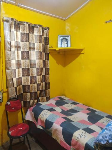 a yellow bedroom with a bed and a clock on a shelf at Kumar Guest House in Shimla